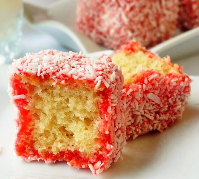 Strawberry Lamingtons, a.k.a. Strawberry Coconut Cake Squares, moist cubes of homemade vanilla cake get soaked in a combination of strawberry jello and jam and then rolled in coconut. 