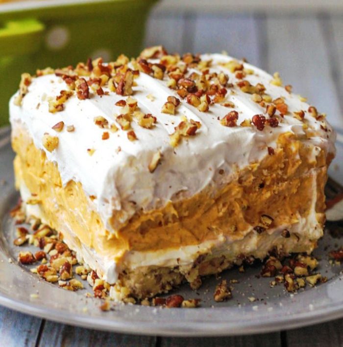 Tasty 4 layer pumpkin delight dessert starts with a crunchy pecan crust topped with creamy pumpkin, cream cheese, and whipped cream layers.