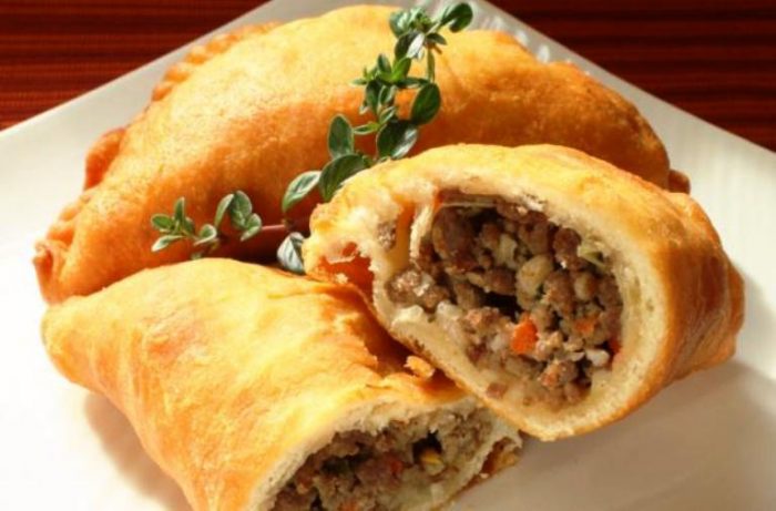 Ground beef and pork flavored with garlic, green onion, and red bell pepper.  The filling tucked into a homemade dough and deep fried. 