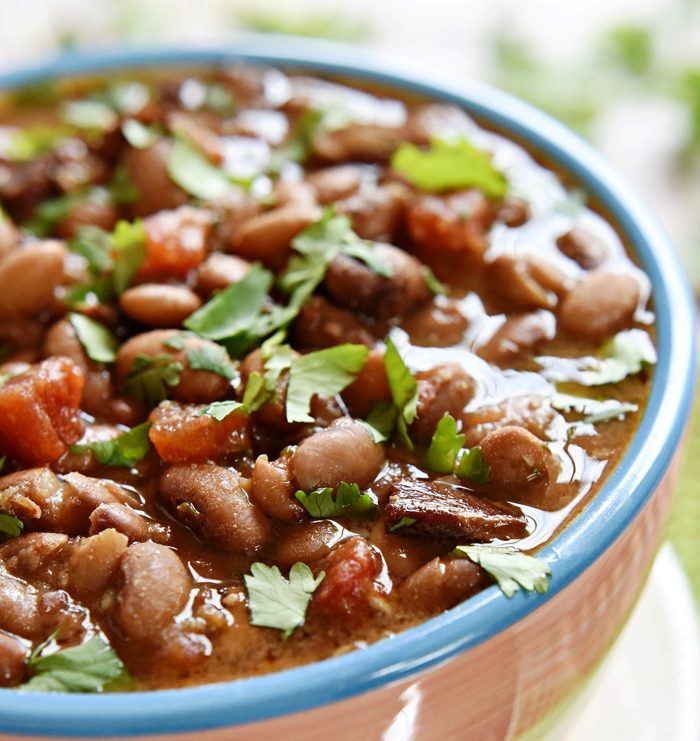 Charro Beans are flavored with bacon, garlic, tomatoes, green chiles, jalapeños, cilantro, and spices and cooked in the slow cooker to make them hands-off and truly effortless…the perfect side dish for Mexican food!