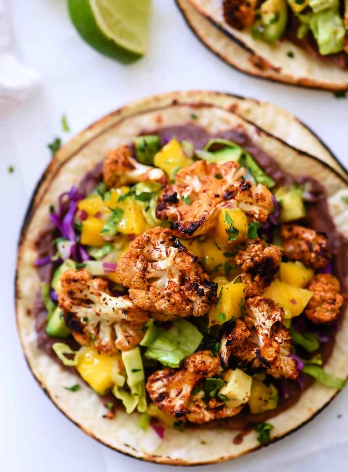 These easy to make vegetarian tostadas with refried black beans, Sriracha lime roasted cauliflower, and mango avocado salsa, bring big flavor for the perfect, weeknight-friendly 30-minute dinner.