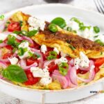 Tomato Feta Cheese Omelette Idea for breakfast. Easy homemade recipe with salad of cherry tomato, goat feta cheese and onion meal.
