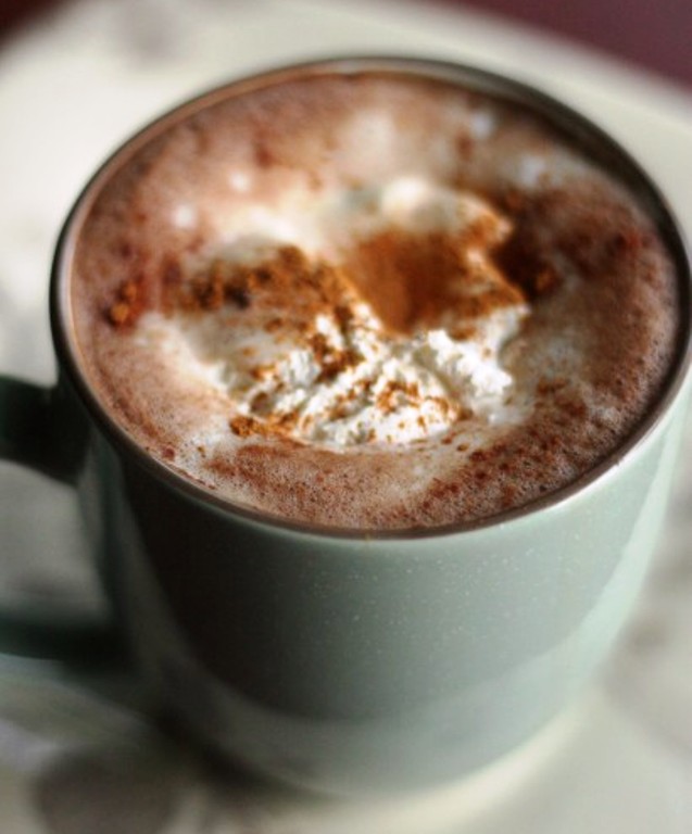 Add cocoa, sugar, and milk to a coffee cup and stir. Add hot coffee. Top with whipped cream and cinnamon.