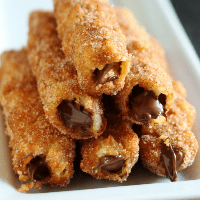 Nutella Stuffed Churros feature a homemade pastry that is deep fried until golden, coated in sweet cinnamon sugar, and stuffed with Nutella.