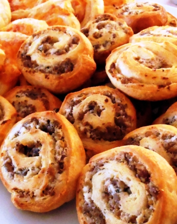 Flavorful sausage and cream cheese are rolled up in crescent dough, sliced and baked to make the perfect party food!