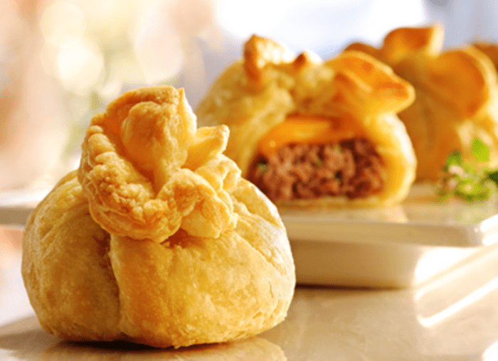 Petite burgers get jazzed up with melted cheese and puff pastry to create an appetizer everyone will adore. Vary the cheese and ground meat in a multitude of ways for ever-new, go-to hors d'oeuvres.