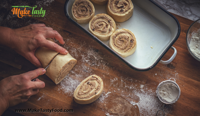 Newly rolled cinnamon dough being cut into roll sizes to bake 