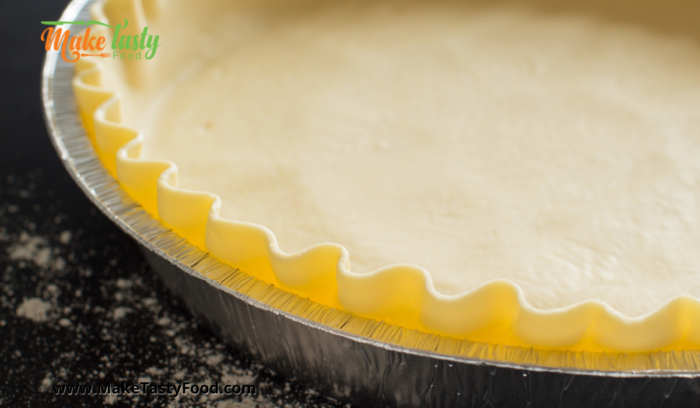 a larger tart bowl filled with shortbread crust to be baked.