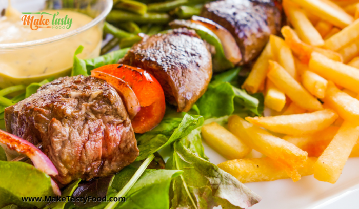 A grilled beef and peppers sosatie or kabab with salad and chips