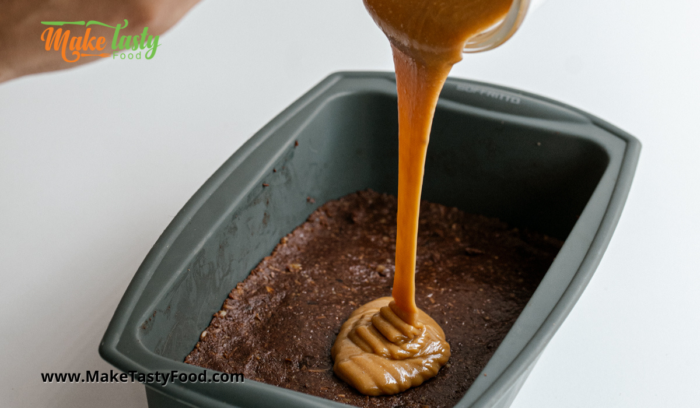 pouring the mixed caramel onto the chocolate brownie base to chill