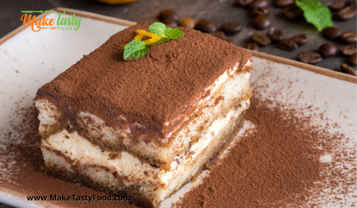 A slice of tiramisu tart dusted with cocoa powder on a plate. 