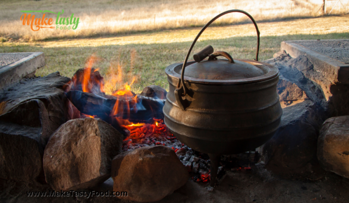 an open outside fire and coals with a pot cooking
