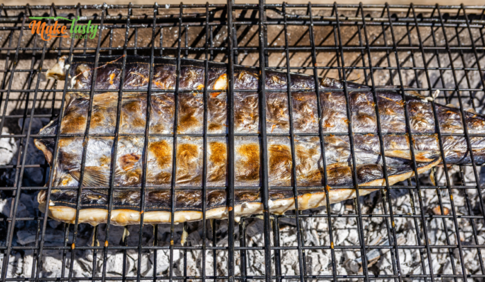 snoek fish being grilled and turned on coals