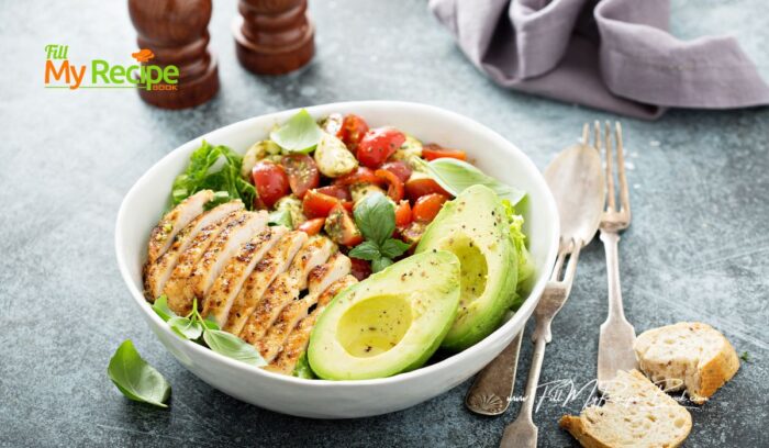 A simple Grilled Chicken Caprese Lunch Bowl with avocado recipe for summer. Served with lettuce and cherry tomatoes and cheese.