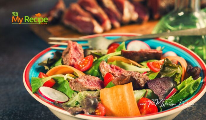 A delicious Spicy steak salad lunch recipe for summer. Healthy bowl of veggies and cherry tomatoes on a lettuce, baby spinach bed and a simple dressings.