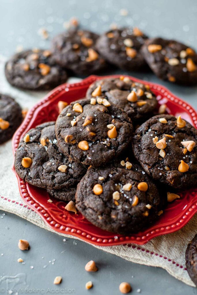 These super soft baked fudge cookies are filled with butterscotch and sweet salty toffee bits. Top with sea salt to make a totally irresistible chocolate cookie!