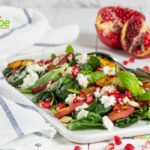 A Fresh Pomegranate Feta Salad with grilled peaches and spinach leaves. A side dish or breakfast meal drizzled with a honey dressing.