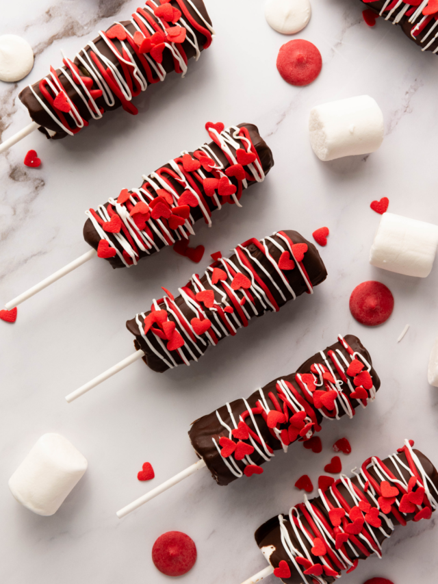 Simple Marshmallow Pops for Valentine’s idea for kids. Stack three marshmallows on a stick, dip in chocolate, and add heart sprinkles.