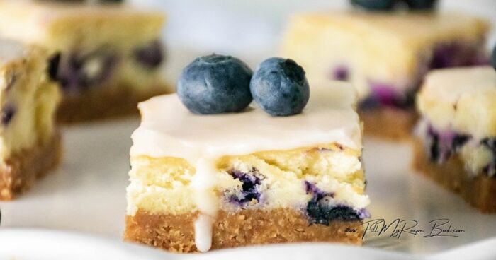 These Oven Baked Lemon Glazed Blueberry Cheesecake Bars feature a crunchy cookie crust, fluffy marshmallow cream cheese filling, with lemon glaze.