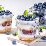 Layered Blueberry Parfait Dessert Recipe. A no-bake delight features crushed biscuits, honey infused cheesecake, and jam, all topped with fresh berries.