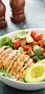 A simple Grilled Chicken Caprese Lunch Bowl with avocado recipe for summer. Served with lettuce and cherry tomatoes and cheese.
