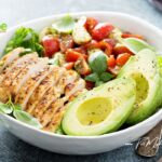A simple Grilled Chicken Caprese Lunch Bowl with avocado recipe for summer. Served with lettuce and cherry tomatoes and cheese.