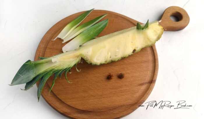 1. Cut a small section off the pineapple along with the leaves. Make incisions, insert the leaves wings, beak and black pepper eyes.
(For the recipe, choose a small pineapple and a juicy lemon. Give preference to a ripe banana. All ingredients are best refrigerated before cooking.)