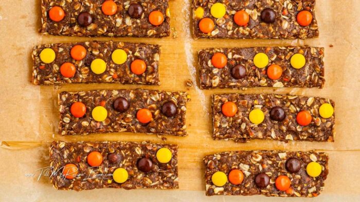 Allow the bars to thaw slightly so they are pliable, and top with extra Reese’s Pieces by gently pushing them onto the tops of each bar.
