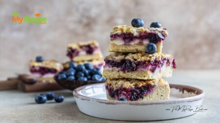 Baked Homemade Blueberry Crumble Cheesecake Bars, buttery shortbread base, cheesecake, juicy blueberry layers, with crumbed almond topping.