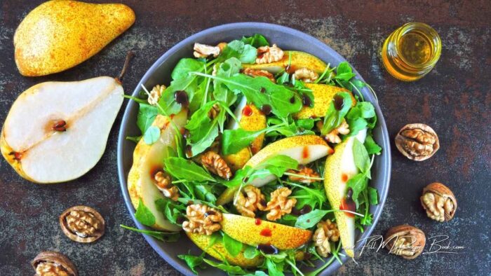 Place leaves in a salad bowl to serve. Add the pears, and walnuts, and toss lightly then drizzle a little dressing over the pears, and serve in the center of the table for all to help themselves.