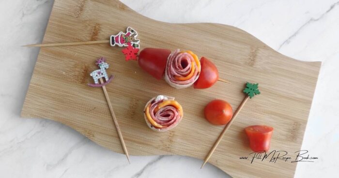 Cut the tomatoes in half. Assemble the skewer. Thread the tomato half, then the roll, and then the tomato again. Garnish with parsley leaves. Arrange the appetizer on a board and serve.