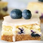 These Oven Baked Lemon Glazed Blueberry Cheesecake Bars feature a crunchy cookie crust, fluffy marshmallow cream cheese filling, with lemon glaze.