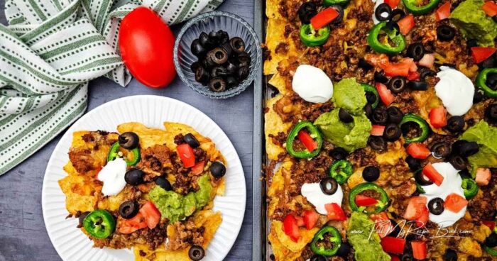 Cook the ground beef in a medium skillet over medium heat, breaking the meat apart as it cooks, until no longer pink. Drain any grease, then mix in taco seasoning and water.
Cut the jalapeno and tomato.
Arrange the tortilla chips on the baking sheet.
Drop spoonful's of refried beans over the tortilla chips, then sprinkle ground beef over them. Cover with the cheese.
Arrange jalapeno slices over the top.
Bake for 12 minutes.