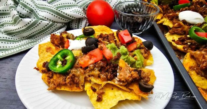 Remove from the oven and drop dollops of guacamole and sour cream over the nachos, then sprinkle with olives and tomatoes.