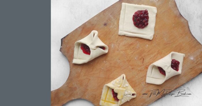 Use the back of a knife to create decorative stripes. Place 1 teaspoon cranberry jam in the center of each square. Fold the opposite corners toward the center, overlapping each other, to form an envelope. Carefully pinch the closure to prevent it from opening during baking. Separate the egg white and yolk. Brush the hearts with egg white and secure them to the letter. Add a Valentine's Day card if desired.