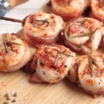 Juicy oven baked bacon wrapped chicken skewers glazed with butter, and thyme. A sweet and savory recipe that’s easy for weeknights.